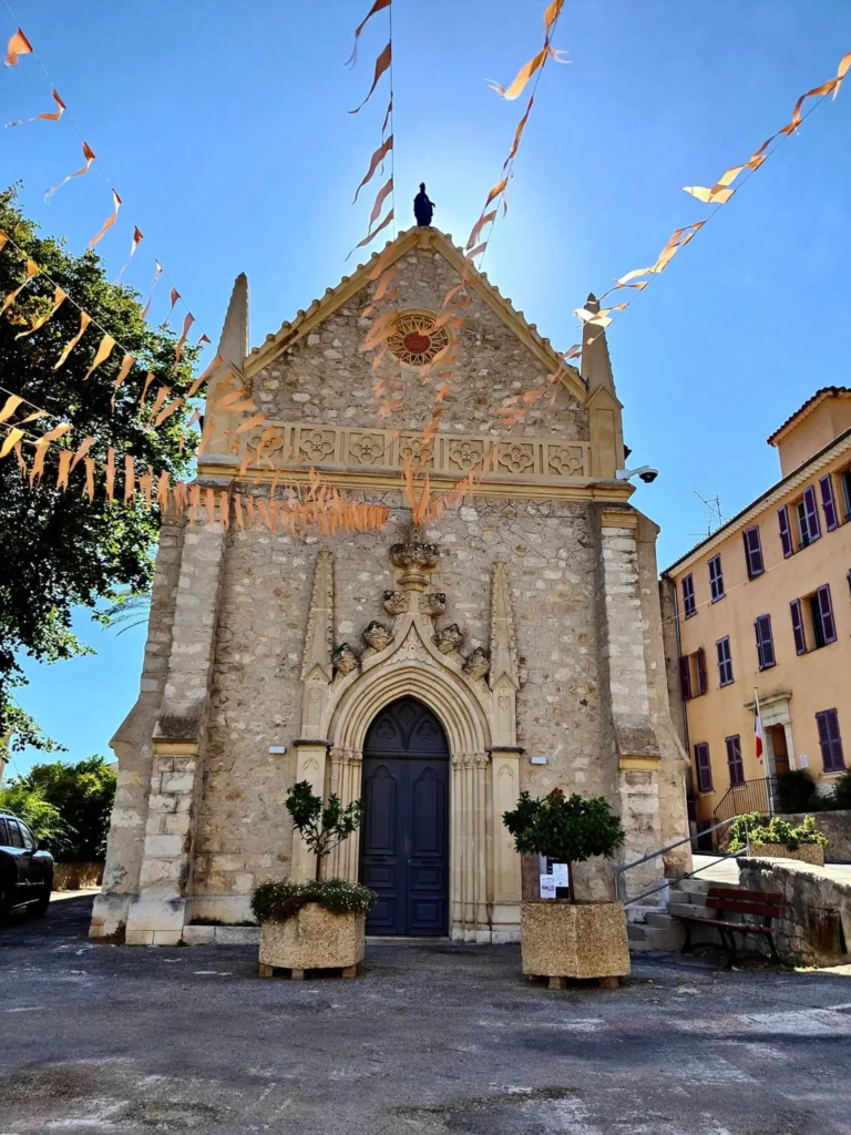 Façade principale d'une église médiévale en pierre calcaire au Bar-sur-Loup, avec un porche d'entrée sculpté de style gothique flammé. @jeanpaul 2025