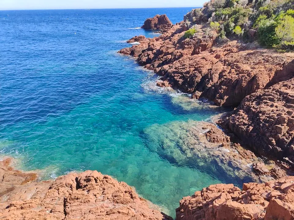 Vue du littoral du massif de l'Estérel, avec des roches volcaniques rouges s'avançant dans une mer Méditerranée au dégradé de turquoise et de bleu profond sous le soleil. @jeanpaul 2025
