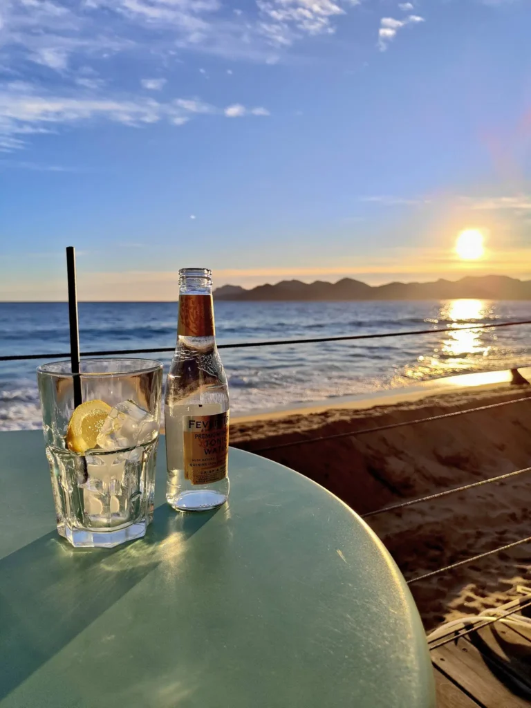 Une image lumineuse et estivale montrant un moment de détente sur une plage privée ou une terrasse de la Croisette.