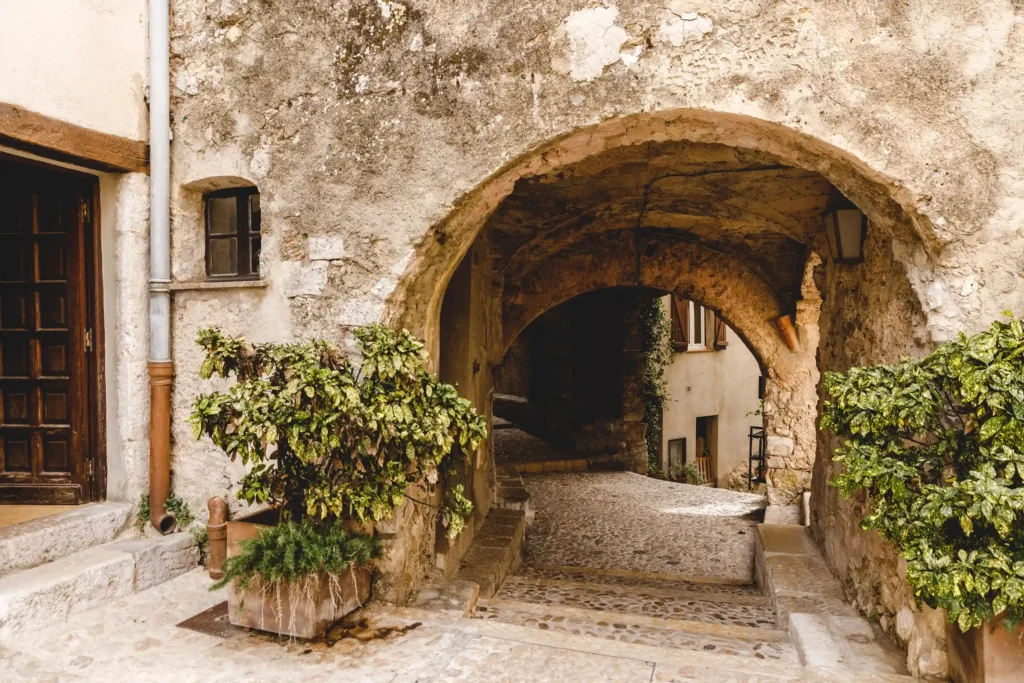 Ruelle pavée médiévale sous un passage voûté en pierre dans le village de Sainte-Agnès.