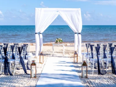 Arche de mariage en voile blanc et chaises d'invités installées sur le sable blanc face à la mer pour un mariage en bord de mer Côte d’Azur.