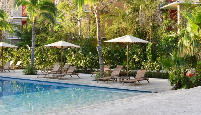 Piscine extérieure et transats ombragés sous les palmiers comme dans un hotel saint tropez luxe d'exception.