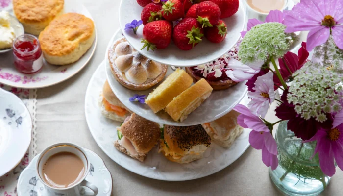 Présentoir à étages garni de fraises fraîches, pâtisseries, scones et petits sandwichs pour savoir où prendre le thé sur la Côte d'Azur.