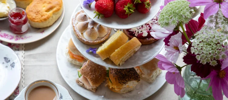 Présentoir à étages garni de fraises fraîches, pâtisseries, scones et petits sandwichs pour savoir où prendre le thé sur la Côte d'Azur.