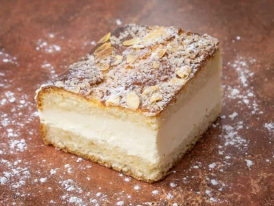 Part de tarte tropézienne avec crème onctueuse, amandes effilées et sucre grain, emblème des spécialités de Saint-Tropez.