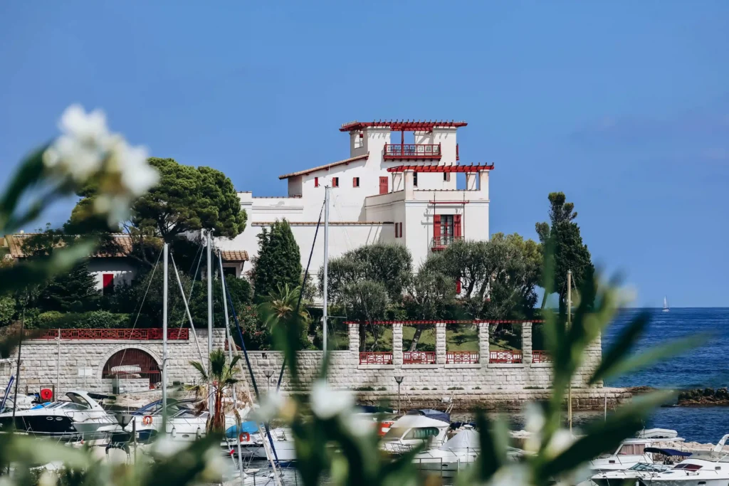 Façade blanche de la Villa Kérylos de style grec antique surplombant le port de plaisance et la mer Méditerranée à Beaulieu-sur-Mer.
