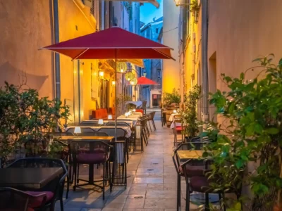 Terrasses de restaurants à Saint-Tropez installées dans une ruelle pittoresque aux façades ocre, éclairées par des lanternes chaleureuses en soirée.