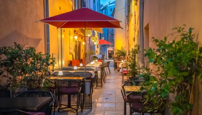 Terrasses de restaurants à Saint-Tropez installées dans une ruelle pittoresque aux façades ocre, éclairées par des lanternes chaleureuses en soirée.