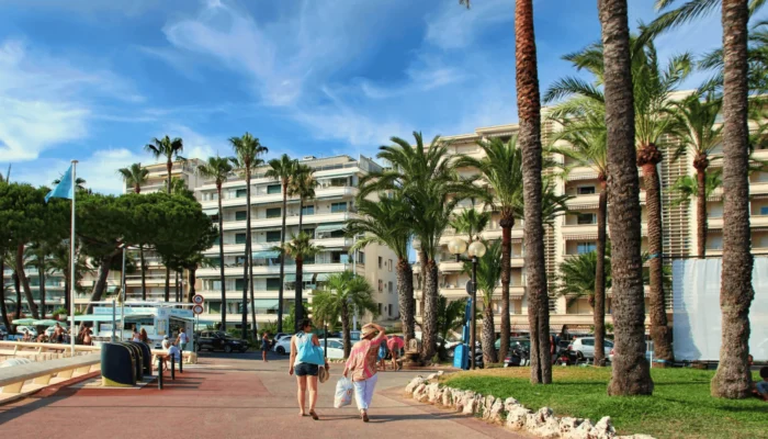 Promenade de la Croisette à Cannes, bordée de palmiers, plages et hôtels de luxe.