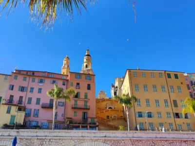 Vue pittoresque de la ville de Menton sur la Côte d'Azur, ses maisons colorées s'étendant du littoral méditerranéen aux collines, sous un ciel bleu