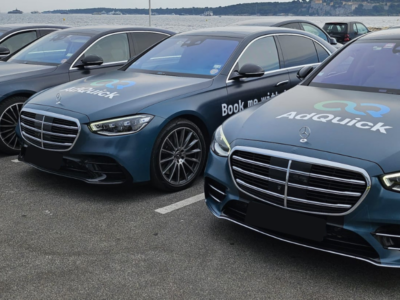 Alignement de quatre berlines de luxe Mercedes Classe S bleu nuit floquées du logo AD QUICK sur un parking en bord de mer, illustrant un service de chauffeur privé pour entreprise haut de gamme.