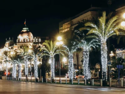 Promenade des Anglais à Nice illuminée la nuit avec des palmiers décorés et des lumières festives de Noël, reflétant la tradition de Noël locale.