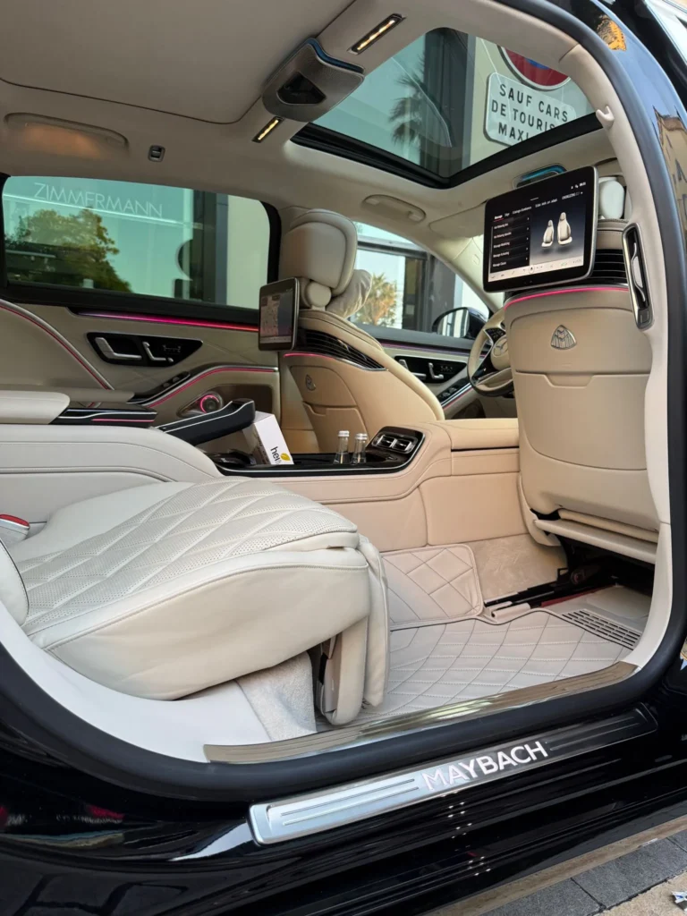 Intérieur luxueux en cuir blanc d'une Mercedes-Maybach Classe S avec écrans vidéo, toit panoramique et éclairage d'ambiance LED pour un service de chauffeur privé pour entreprise.