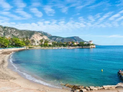 Baie des Fourmis à Beaulieu-sur-Mer avec la Villa Kérylos en arrière-plan, plage de galets, mer turquoise et yachts.
