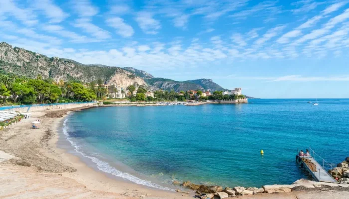 Baie des Fourmis à Beaulieu-sur-Mer avec la Villa Kérylos en arrière-plan, plage de galets, mer turquoise et yachts.