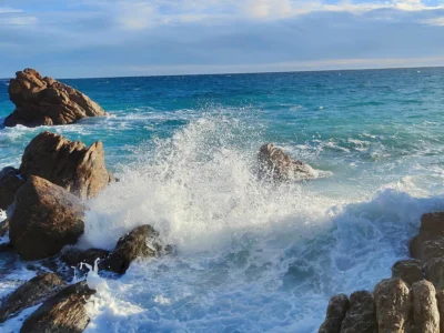 Vue de la Plage des Rochers à Cannes La Bocca montrant les formations rocheuses ocre rouge, le sable fin et l'eau cristalline de la Méditerranée avec le massif de l'Estérel en arrière-plan. @jeanpaul 2025