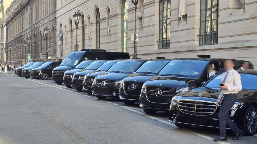 Alignement de berlines Mercedes Classe S, vans Classe V et Sprinter EDEN CAB avec chauffeur privé en costume devant un bâtiment officiel pour une mission diplomatique.