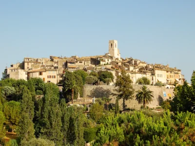 Vue panoramique de Saint-Paul-de-Vence perché sur sa colline, avec ses imposants remparts de pierre dorée entourant le village médiéval, sous la lumière éclatante du soleil provençal.