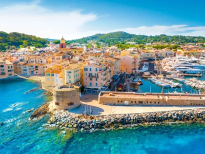 Vue aérienne panoramique du port de Saint-Tropez, avec les yachts, les maisons colorées et la Citadelle en arrière-plan.