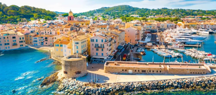 Vue aérienne panoramique du port de Saint-Tropez, avec les yachts, les maisons colorées et la Citadelle en arrière-plan.