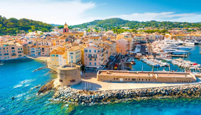 Vue aérienne panoramique du port de Saint-Tropez, avec les yachts, les maisons colorées et la Citadelle en arrière-plan.