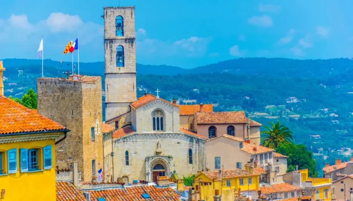 Vue sur la cathédrale Notre-Dame-du-Puy de Grasse, entourée de bâtisses provençales sous un ciel azuréen.